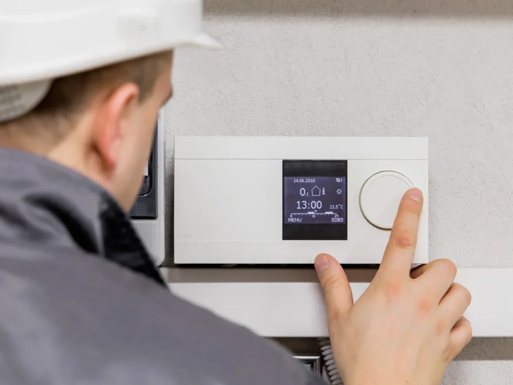 Technician adjusting a smart thermostat during HVAC service in a multi-family building.