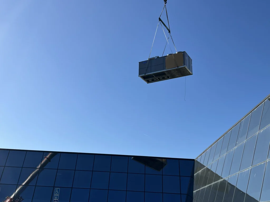 Aquinas HVAC installing a commercial rooftop HVAC unit using a crane.
