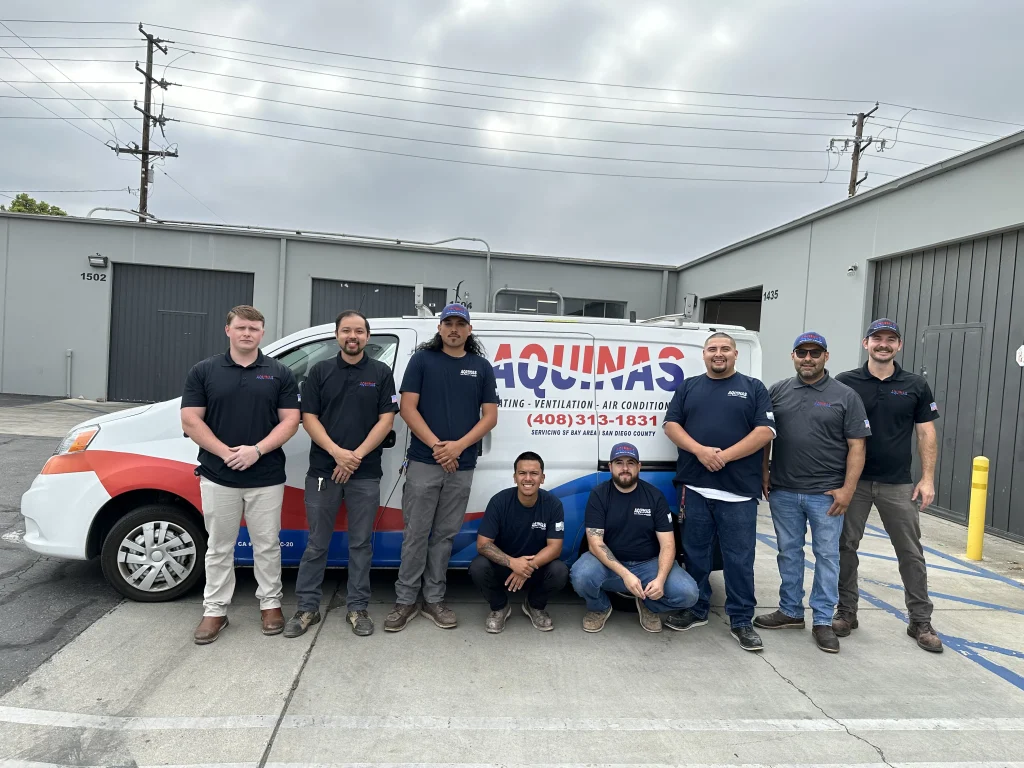 Aquinas HVAC Santa Ana team posing in front of branded service van at company facility.