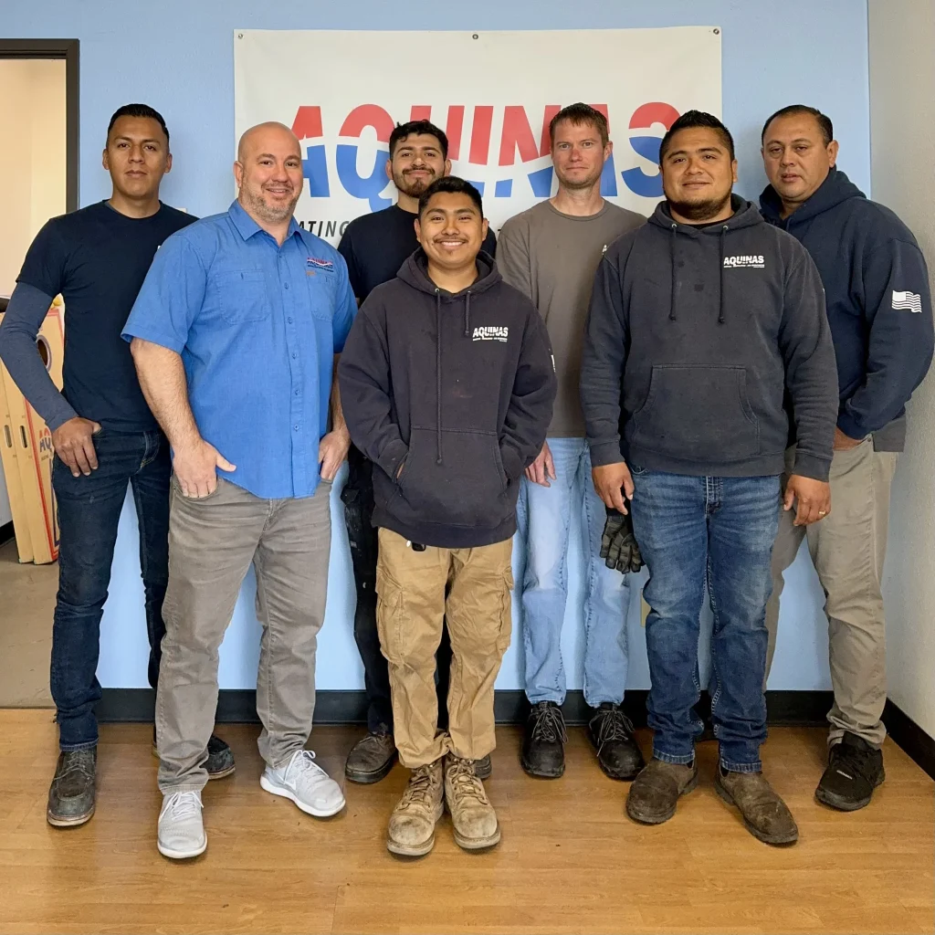 Aquinas HVAC San Diego team standing together in front of company banner.