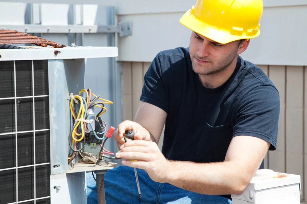 HVAC technician performing emergency repairs on an outdoor air conditioning unit.