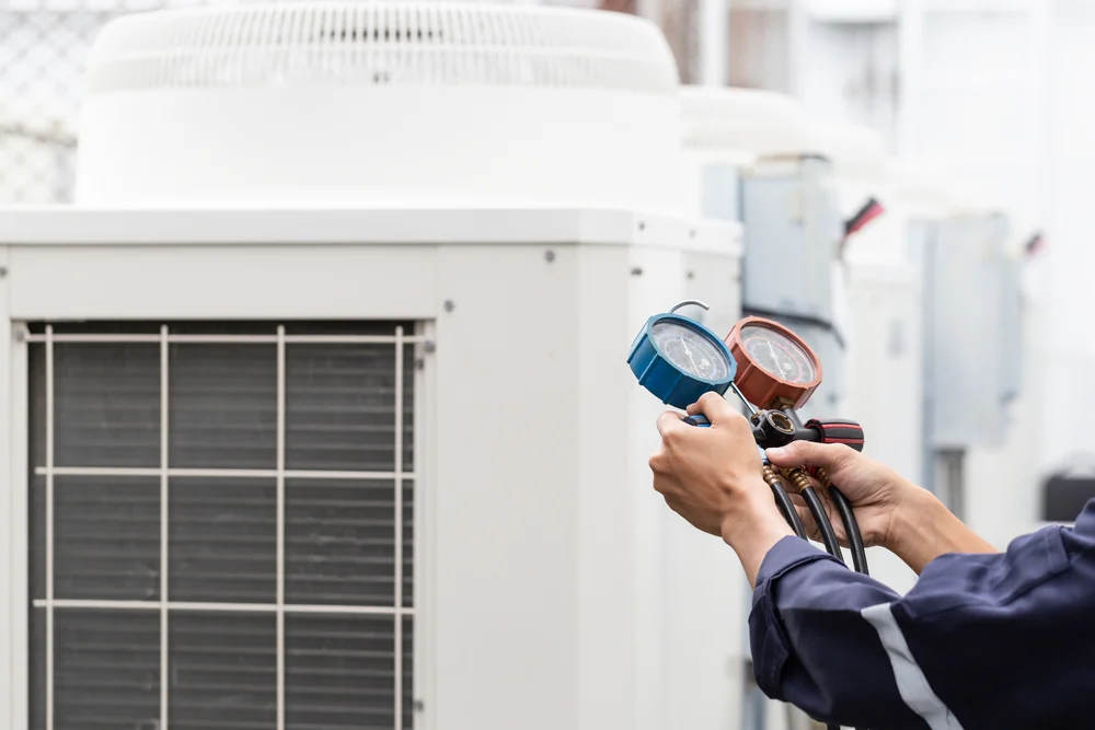 A technician repairing a rooftop commercial HVAC unit on a multi-family property.