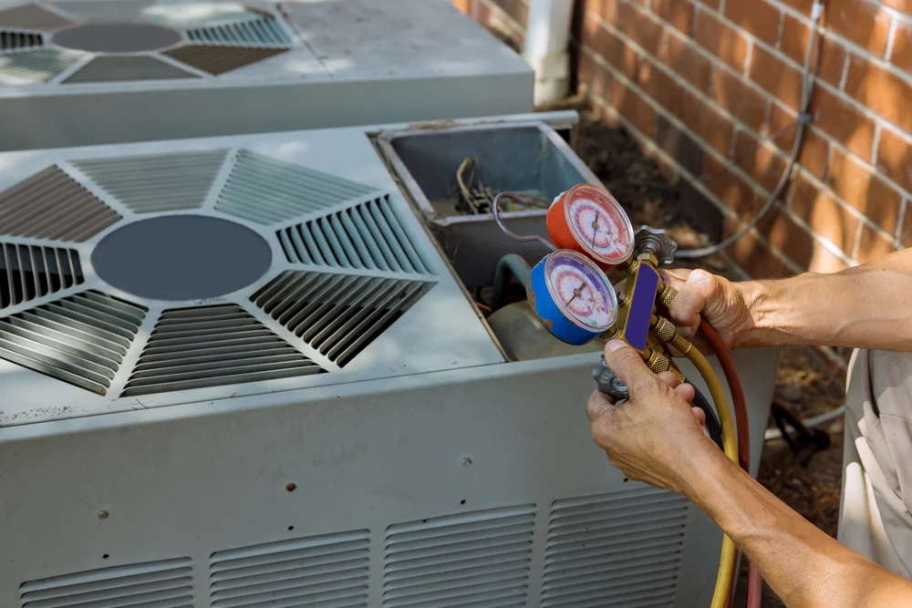 Technician performing routine HVAC maintenance with pressure gauges at a multi-family property.