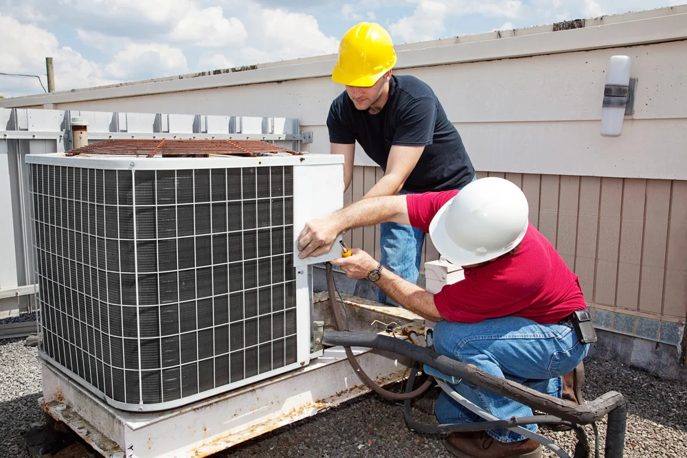 Technician servicing a rooftop commercial cooling unit on a sunny day in California.