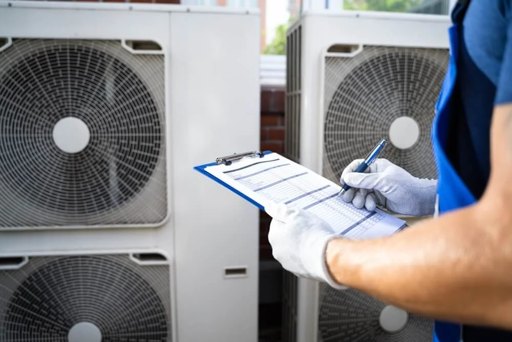 HVAC technician inspecting outdoor units and completing a compliance and safety checklist at a multi-family property.