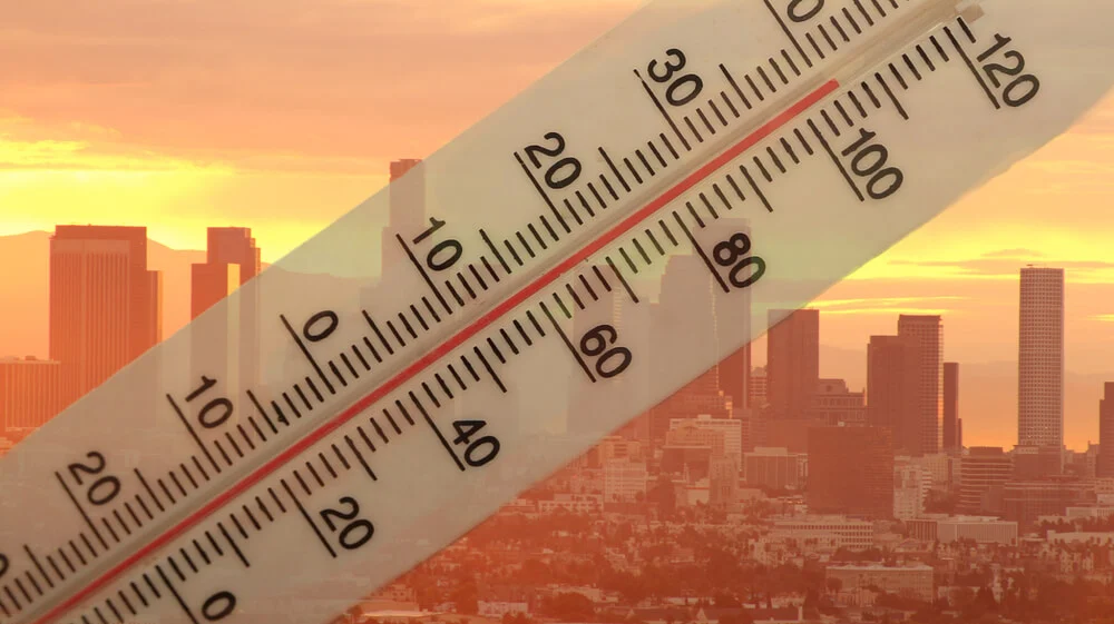 Thermometer showing high temperature over city skyline during heatwave, representing urgency of emergency commercial HVAC repairs.