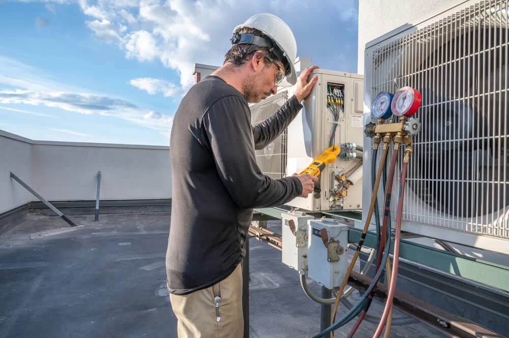 An HVAC technician evaluates a commercial system’s performance—part of the decision to repair or replace.