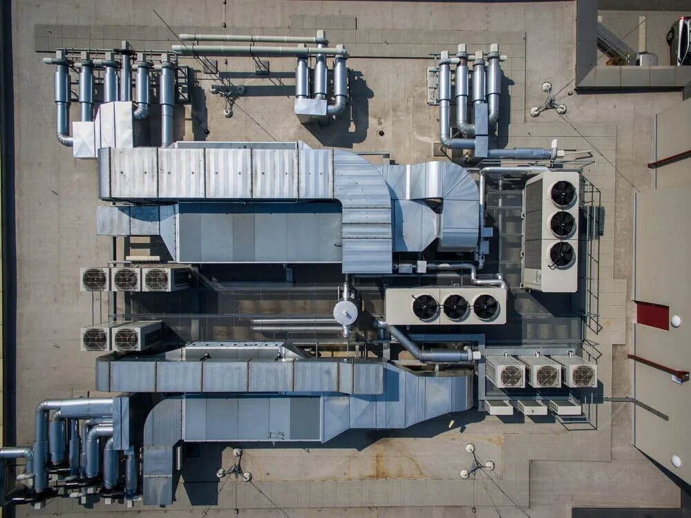Aerial view of commercial HVAC rooftop system on a large California building, showing ductwork, ventilation, and condenser units used in retrofit projects.