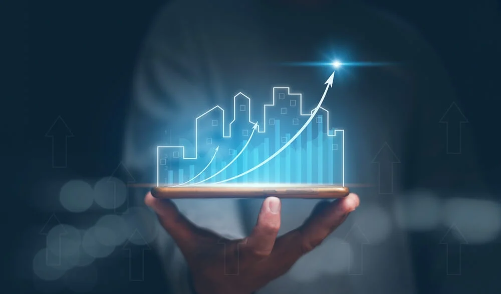 Hand holding a smartphone with a glowing upward arrow and digital city skyline, representing increased commercial property value through strategic HVAC upgrades in California.