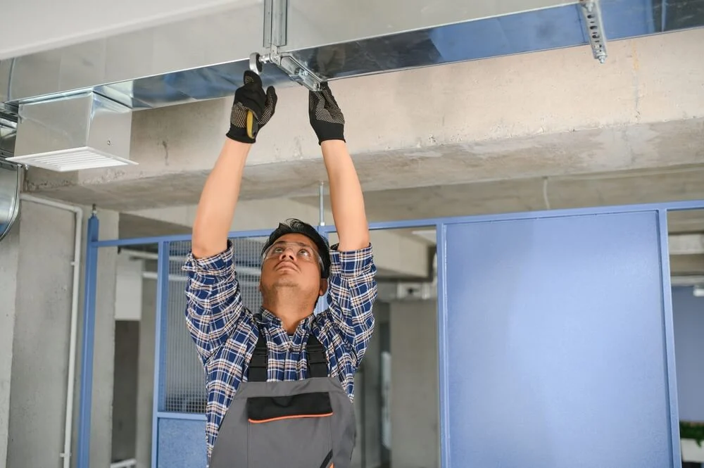 Technician inspecting commercial HVAC ductwork in Orange County