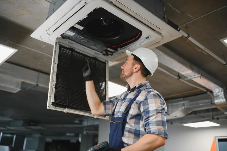 Technician performing commercial HVAC maintenance in a San Diego office building ceiling unit.