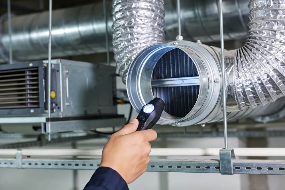 HVAC technician inspecting commercial HVAC ductwork during a preventative system inspection.
