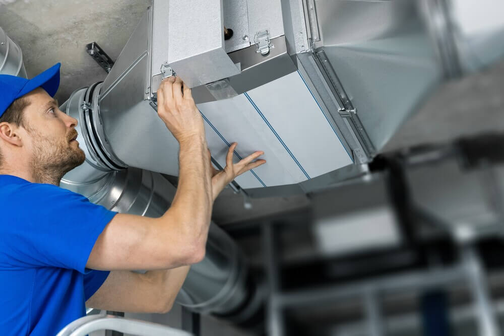 Commercial HVAC technician repairing ductwork in a San Jose building